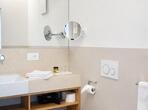 Badezimmer im Apartement Meranerapfel mit WC, Bidet, Waschbecken und einem großen Spiegel.