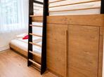 Schlafzimmer im Apartment Gala mit Hochbett aus Holz, schwarzer Leiter und einem weiteren Bett unter dem Fenster.