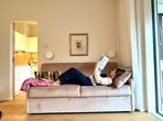 Frau liegt lesend auf dem Sofa der Ferienwohnung Königinapfel.