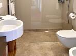 Modernes Badezimmer mit Waschbecken, großer Dusche, WC und Bidet.