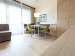 Suite deluxe Champagner con divano, zona salotto, armadio in legno e ampia vetrata con vista sul balcone.