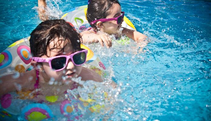 Bambini con salvagenti si divertono a sguazzare in piscina.
