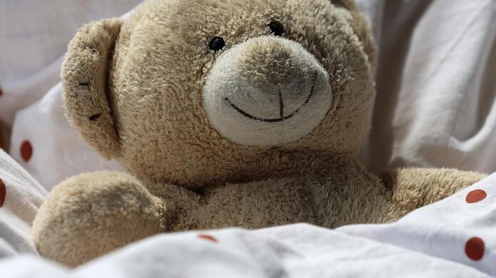 Nahaufnahme von einem Teddybären in einem Bett.