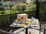 Balkon mit gedecktem Tisch, Stühlen und Blick auf die umliegende Landschaft und Vegetation.