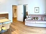 Living area with a wooden table and chairs and a light-coloured sofa with colourful cushions.