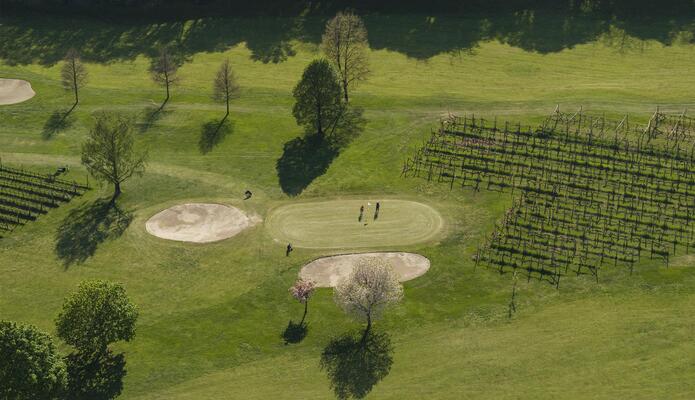 Veduta aerea di un campo da golf con fairway verdi, bunker di sabbia e alberi.