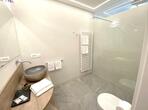 Bathroom in the Calville double room with a toilet, washbasin, large mirror and level-access shower with a glass partition.