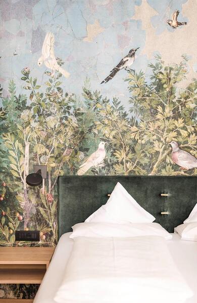 Letto matrimoniale con biancheria bianca, testiera verde e carta da parati raffigurante piante e uccelli allo Zea Curtis.