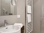 Badezimmer der Ferienwohnung Königinapfel mit Waschbecken, großem Spiegel und Dusche.