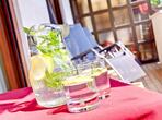 Nahaufnahme von einem Krug mit Wasser, Minze und Zitronenscheiben, daneben zwei Gläser.