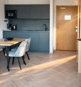 Heller Wohnbereich mit moderner Küchenzeile, Esstisch mit Stühlen, Sofa und Holzdetails im zeitgemäßen Design.