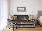 Grey sofa with colourful cushions in the Meranerapfel double room.