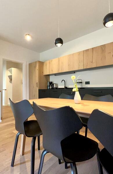 Cucina nell’appartamento Gala con ante in legno, mobili neri e un tavolo in legno con sedie nere.
