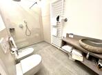 Badezimmer im Apartment Palmengarten mit WC, Bidet, bodengleicher Dusche mit Glasabtrennung und ein Waschbecken.
