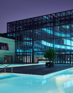 Therme Meran am Abend mit beleuchteten Außenpools.
