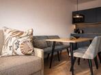 Heller Wohnbereich mit moderner Küchenzeile, Esstisch mit Stühlen, Sofa und im zeitgemäßen Design.