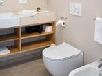 Bathroom in the Meranerapfel double room with a bidet, toilet, washbasin and large wall mirror.